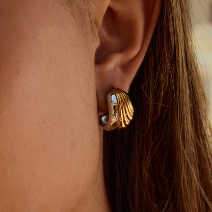 Model wearing thick wavy earrings under sunlight