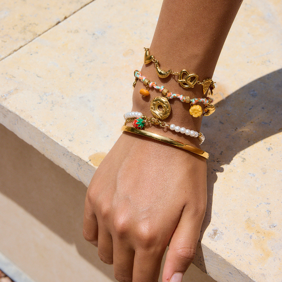 Playful snack-themed charm bracelets on sun-kissed wrist