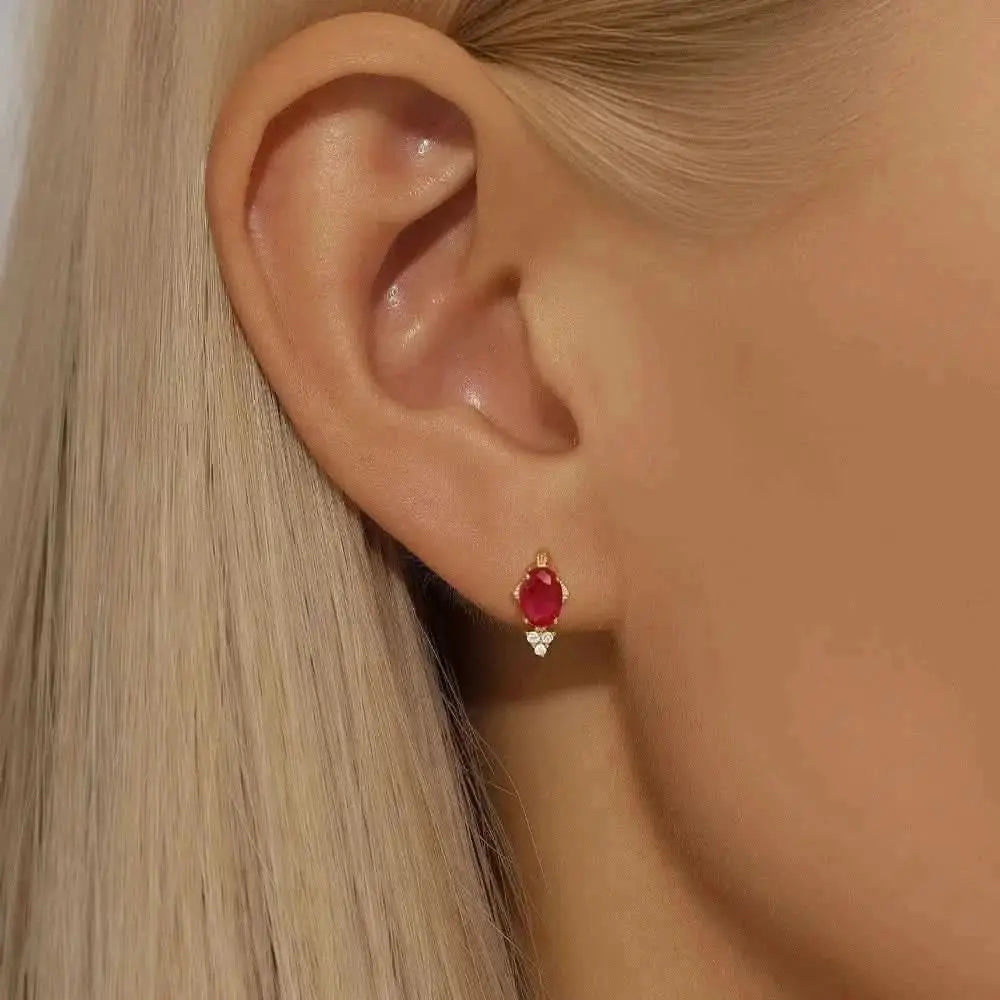 Vintage-inspired gold earrings with a vibrant red stone for a regal look.