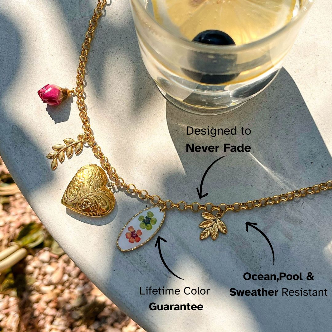 Close-up of floral enamel and heart charms on gold necklace