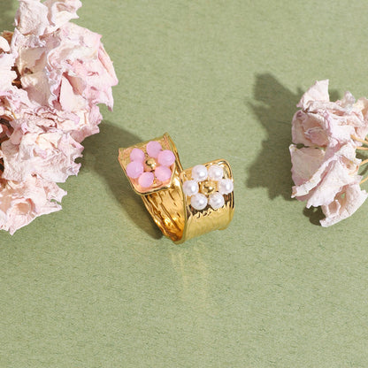 Ring with pearl and pink floral design on green paper background with soft lighting