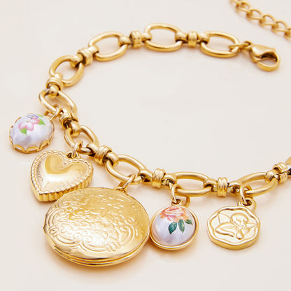 Gold chain bracelet with enamel rose and heart pendants on white background