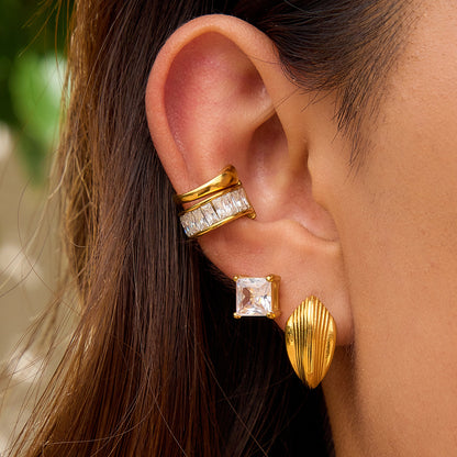 Woman wearing sculptural gold stud earrings with ear cuffs