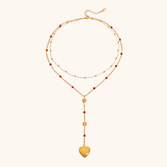 Close-up of gold heart locket necklace with floral charm