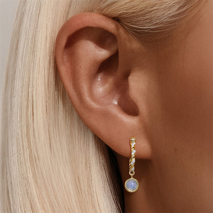 Model wearing gold vintage twist hoop earrings with opal stone drop and zirconia detailing.