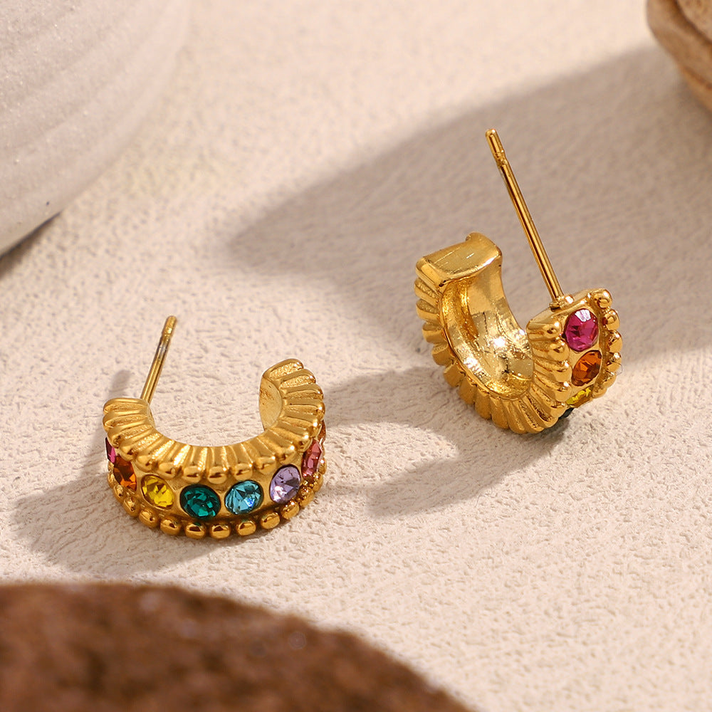 Colorful gem studded gold half hoops photographed in soft daylight
