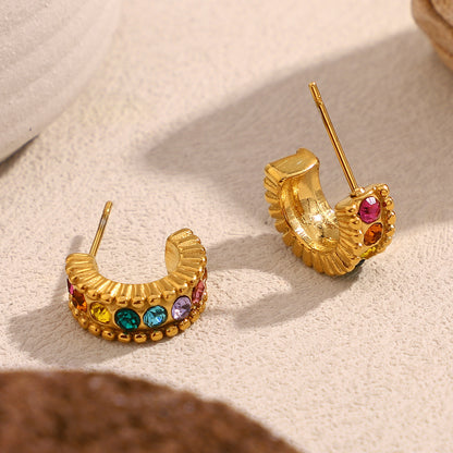 Colorful gem studded gold half hoops photographed in soft daylight