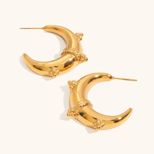 Gold moon-shaped statement earrings displayed on neutral background