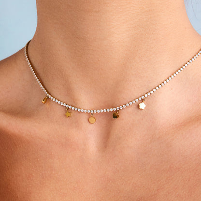 Model wearing a gold tennis necklace with star, heart, and disc charms