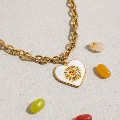 Bold gold link chain necklace with white enamel sun pendant styled with candies