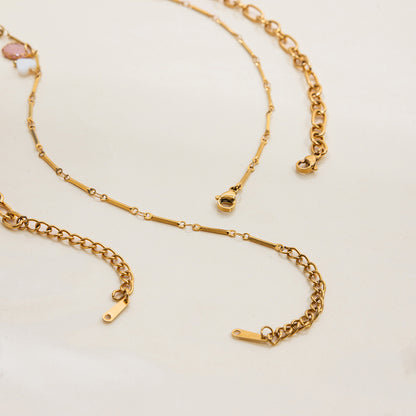 Flatlay of two vintage-style gold necklaces with feminine, romantic charms