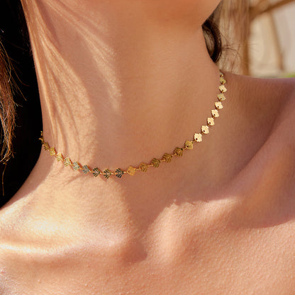 Model wearing gold shell choker necklace under beach sunlight close-up