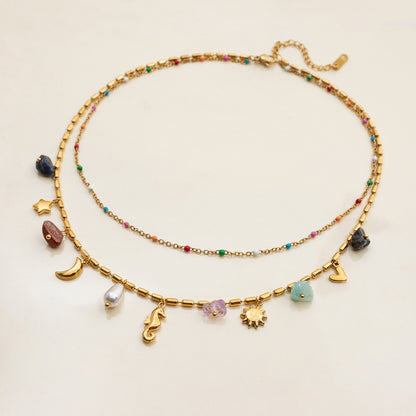 Gold necklace with various charms on a light beige background