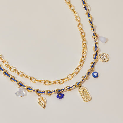 Flatlay of gold blue chain necklace with mixed playful pendants