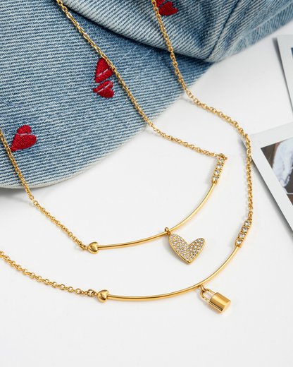 Gold necklace with heart charm on a denim fabric background