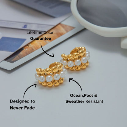 Studio shot of pearl beaded gold huggie earrings on neutral backdrop