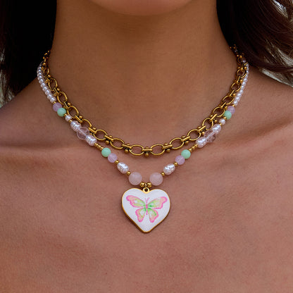 Model wearing heart butterfly necklace with gold chain and pearls