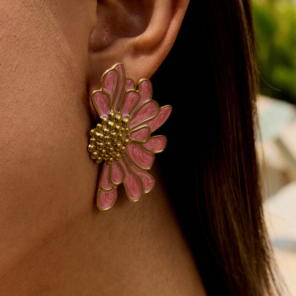 Model wearing pink enamel daisy earrings outdoors in sunlight