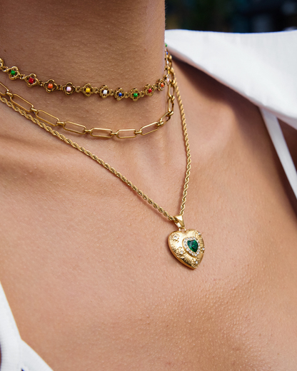Close-up of a person wearing multiple gold necklaces with heart pendants.