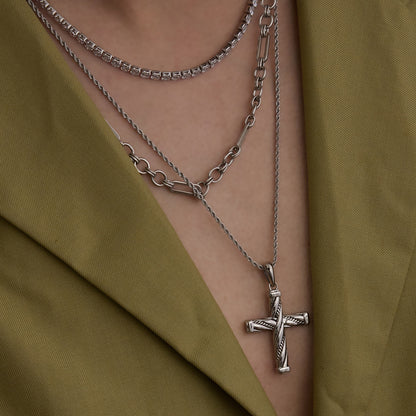 Close-up of stainless steel cross necklace on model in olive green blazer