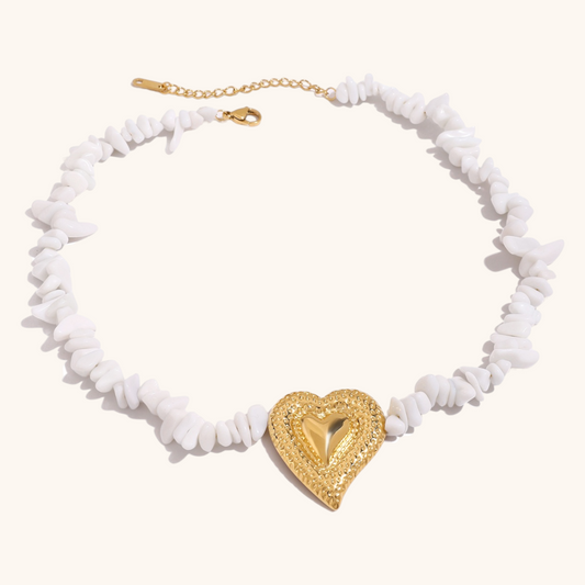 Flat lay of white shell bead necklace with oversized textured gold heart pendant