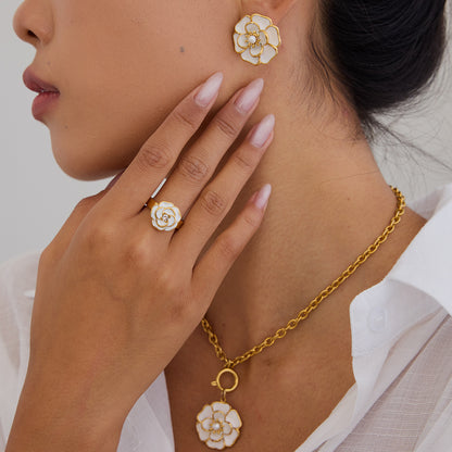 Model wearing matching white enamel flower earrings, necklace and ring with gold finish