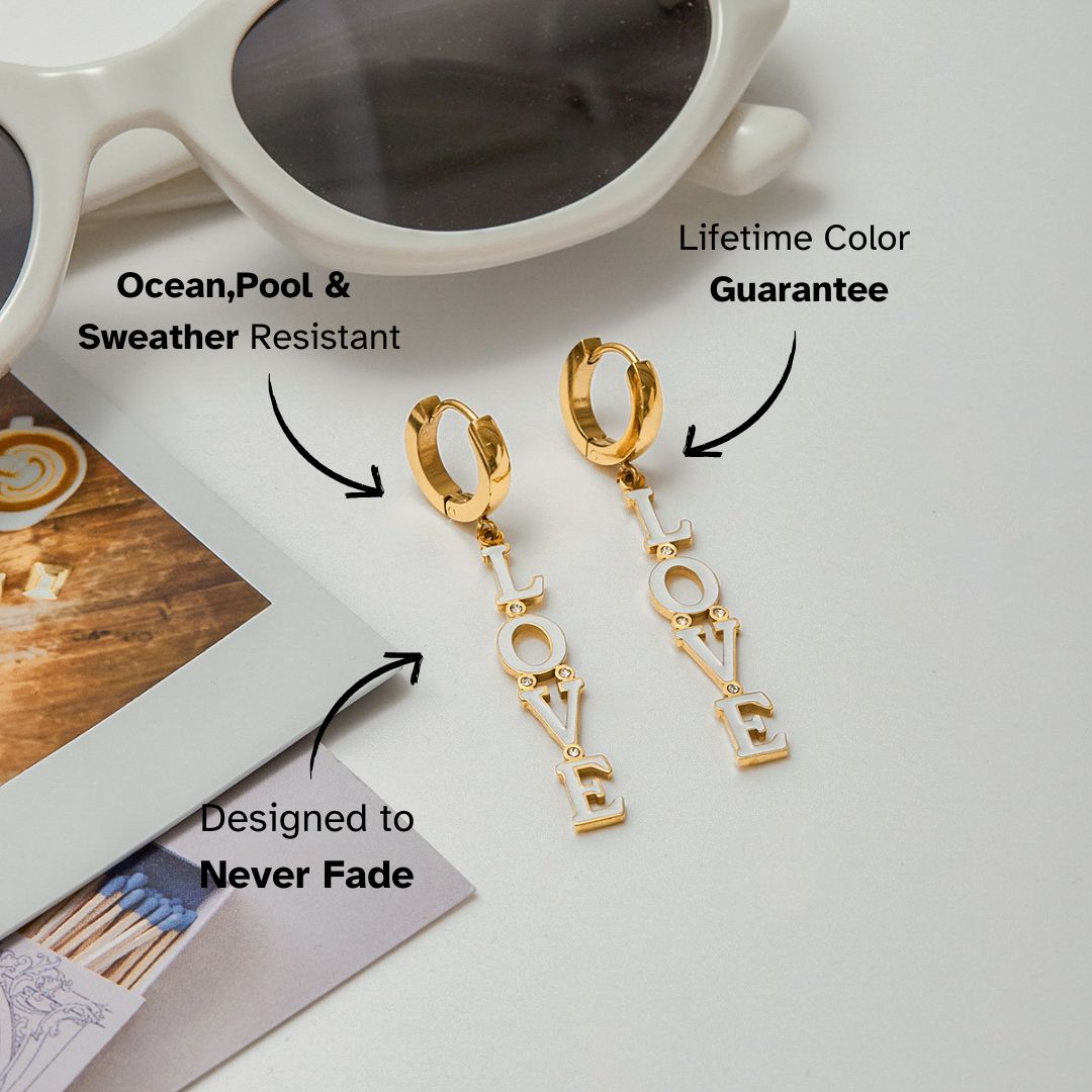Gold script LOVE earrings with a pop of pink, dangling against soft lighting_MiFJewelry