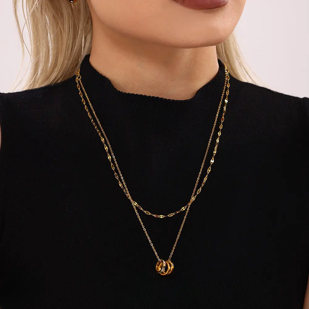 Close-up of model wearing 'With Love' Triple Ring Necklace, showcasing multicolor zircon stones, with a focus on hand styling.