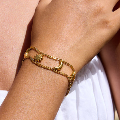 Model wearing layered sun charm bracelet in natural light.