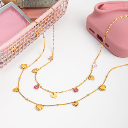 Gold necklace with heart-shaped pendants on a white surface