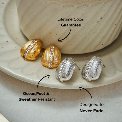 Minimalist display of gold and silver zircon-studded earrings against neutral background