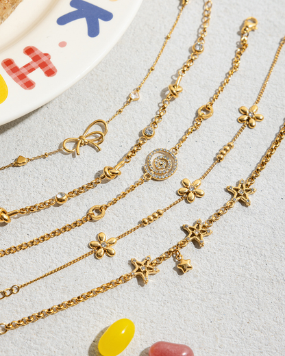 Gold necklaces with various charms on a light gray surface