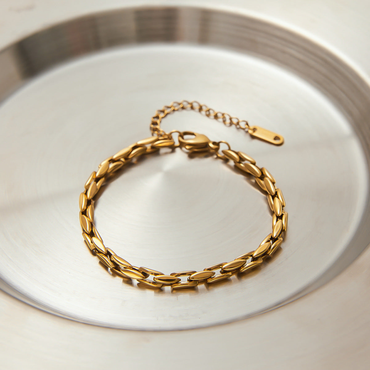 Gold link bracelet displayed in round silver dish, highlighting waterproof and fade-resistant design
