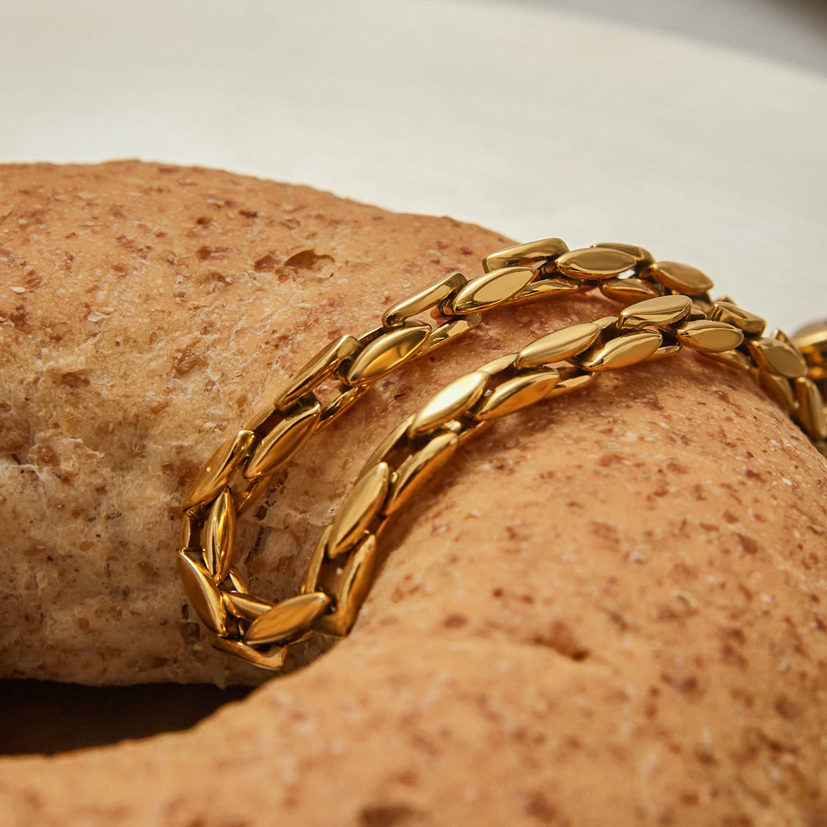 Shiny waterproof gold bracelet styled creatively over bread for lifestyle product shoot