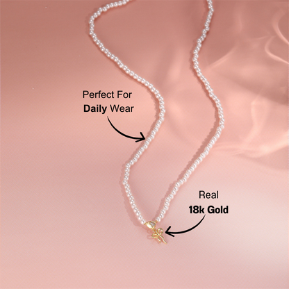 gold-pearl-necklace-pink-background.png – Sophisticated pearl necklace with a 14k gold bow charm, displayed on a soft pink background to highlight its delicate and feminine design.