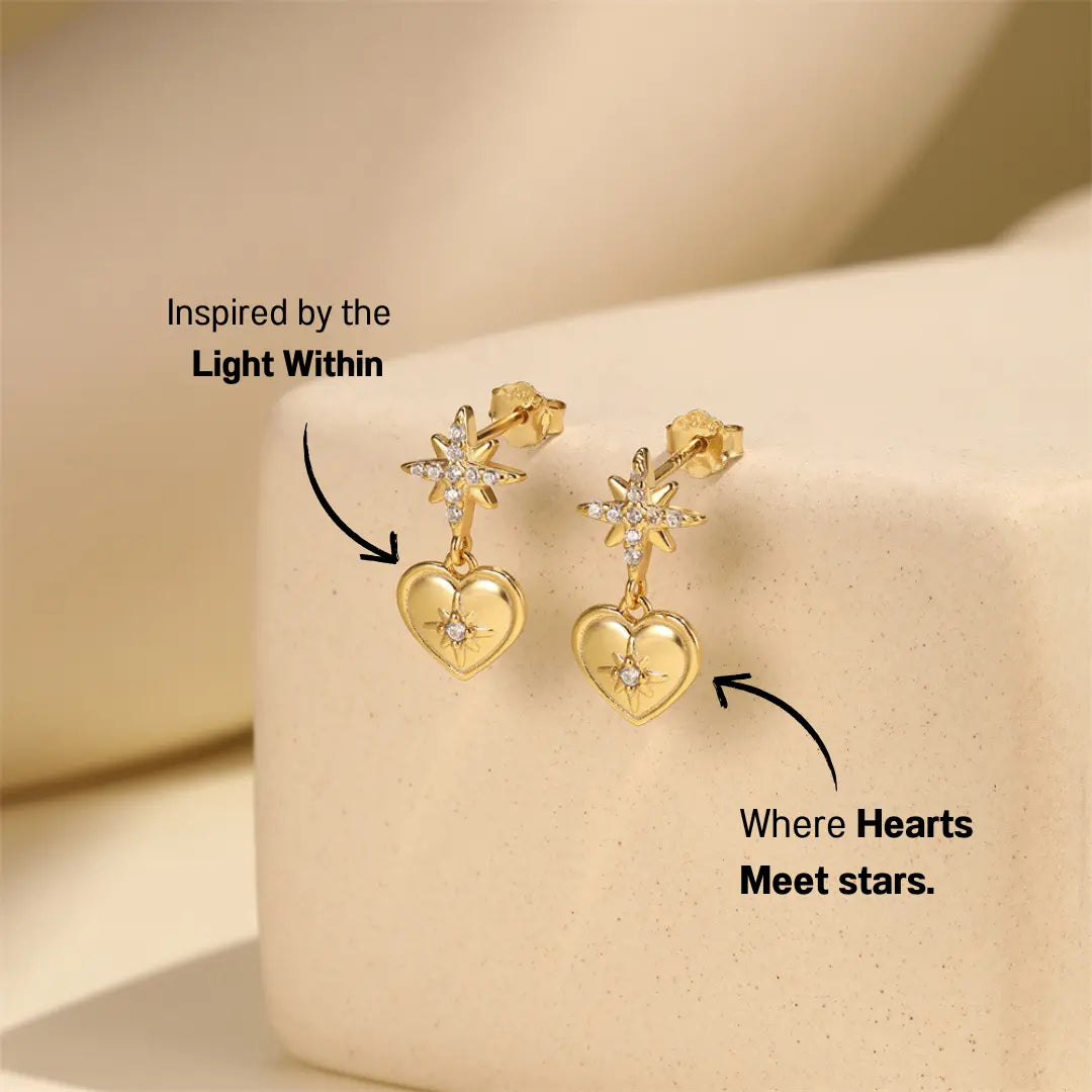 Close-up of gold Heart & Starburst Drop Earrings with zirconia stones on a soft background. Elegant design.