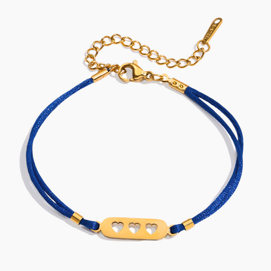 Blue bracelet with gold clasp and heart-shaped tag on a white background