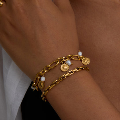 Woman wearing a layered stack of gold chain and coin pearl bracelets, summer jewelry style