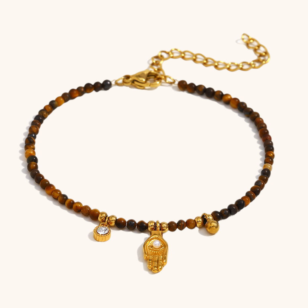 Tiger eye stone beaded bracelet with gold hand and crystal charm on neutral background